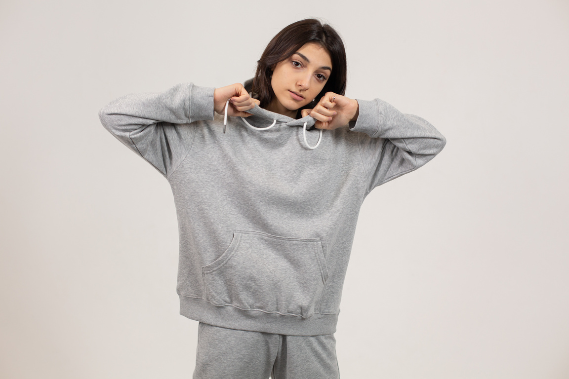 Young woman with hand on hoodie in studio